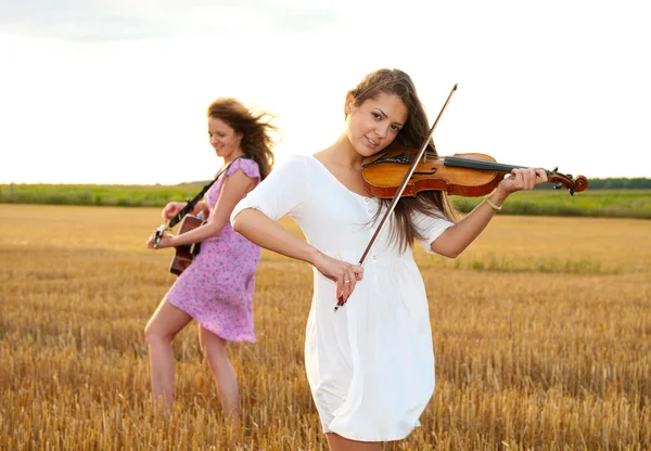 Twee jonge vrouwen spelen gitaar en viool buitenshuis — Stockfoto