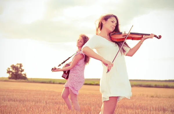 Duas jovens mulheres tocando guitarra e violino ao ar livre — Fotografia de Stock