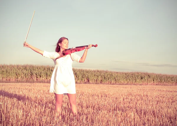 Młoda kobieta trzyma skrzypce i łuk na zewnątrz. Podziel tonowanie. — Zdjęcie stockowe