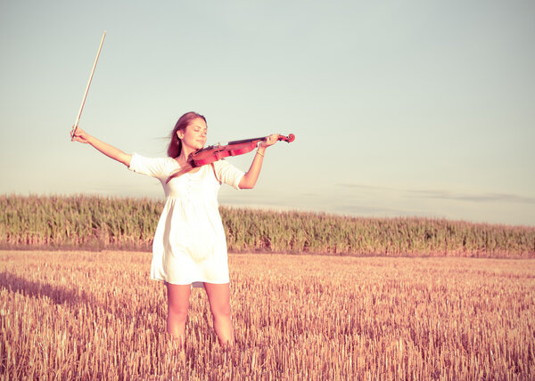 Young woman holding violin and bow outdoors. Split toning.