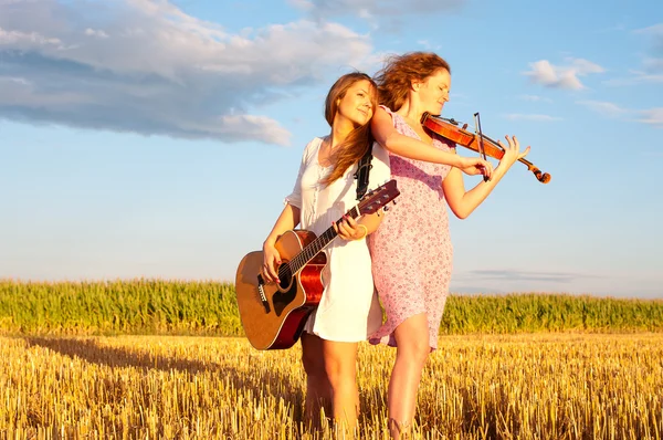 Two young women playing guitar and violin outdoors — Stock Photo, Image