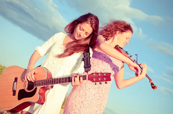 Duas jovens a tocar guitarra e violino ao ar livre. Tonificação dividida — Fotografia de Stock