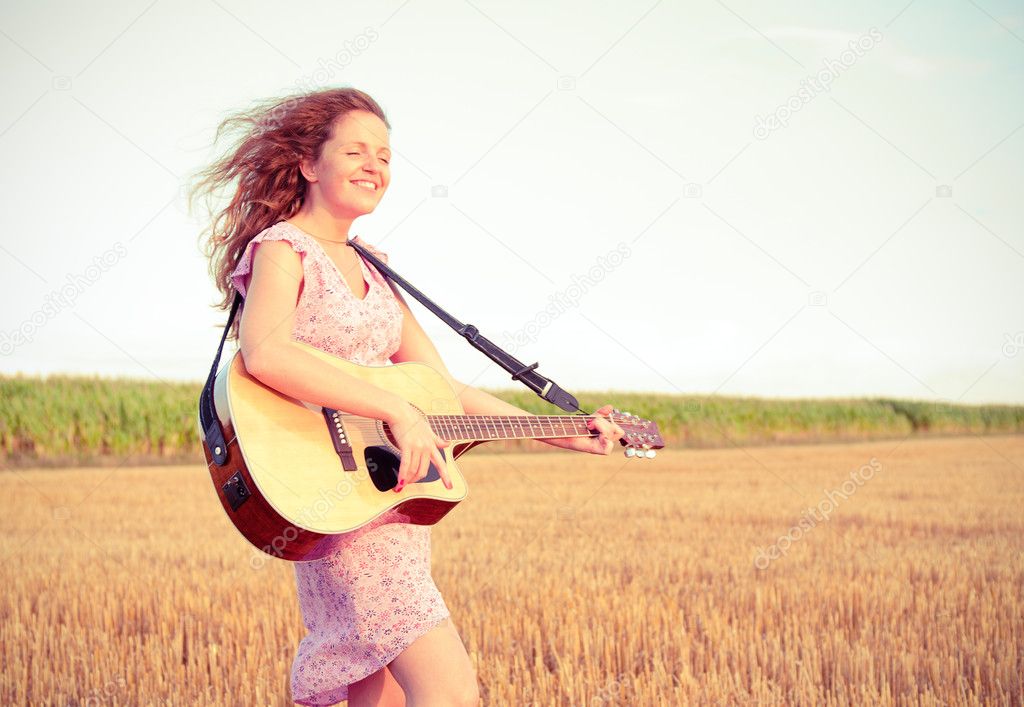 Redhead woman playing guitar outdoors