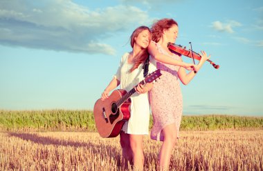 iki genç kadın iskambil gitar ve keman açık havada. Tonlama Böl