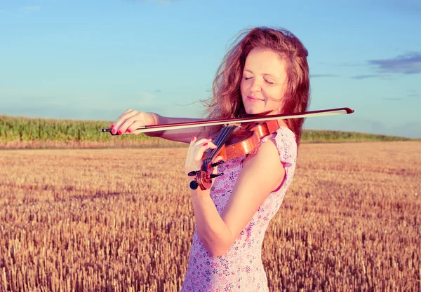 Rothaarige Frau, die draußen auf dem Feld Geige spielt. gespaltene Tonung — Stockfoto