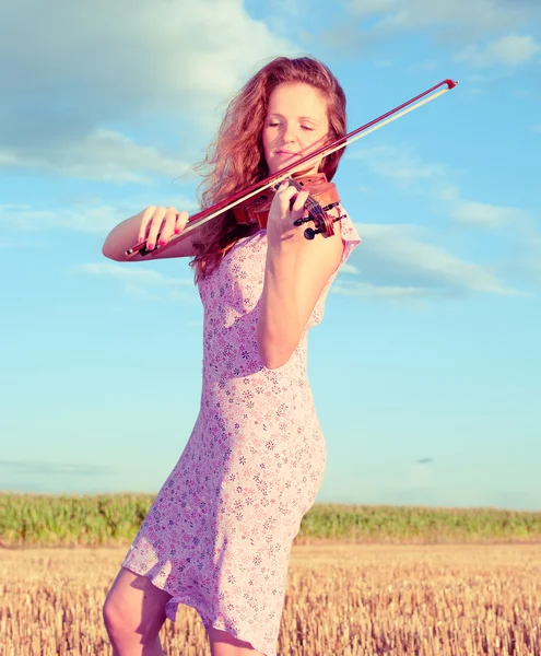 Redhead woman playing violin outdoors on the field. Split toning — Stock Photo, Image