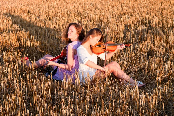 Dos jóvenes tocando la guitarra y el violín al aire libre — Foto de Stock