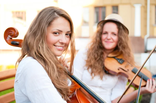Две женщины в дуэте играют на скрипке и виолончели на улице — стоковое фото