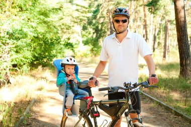 Fathr and little son on bike with child seat clipart