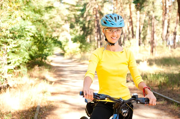 Kvinna på cykeln i soliga skogen — Stockfoto