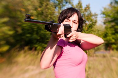 Woman aiming rifle in the summer forest. Lensbaby effect clipart