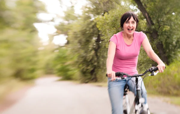 Mulher andando de bicicleta animado na estrada da floresta de verão. Lensbaby ef — Fotografia de Stock