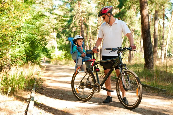 Vader en zoontje op fiets met Kinder-autostoeltje Stockafbeelding