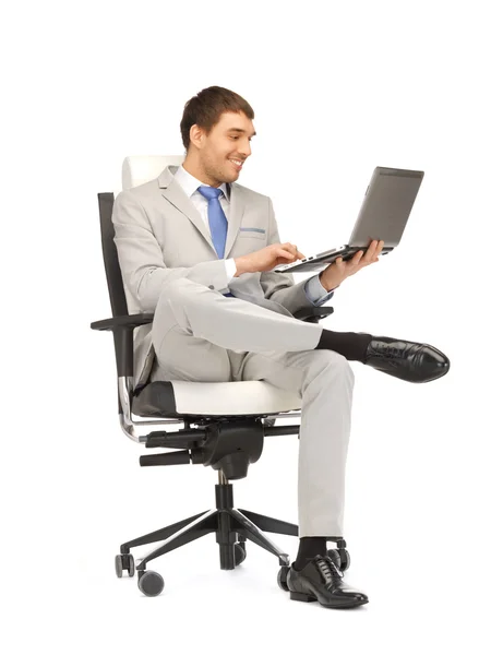 Mladý podnikatel, sedí v křesle s notebookem — Stock fotografie