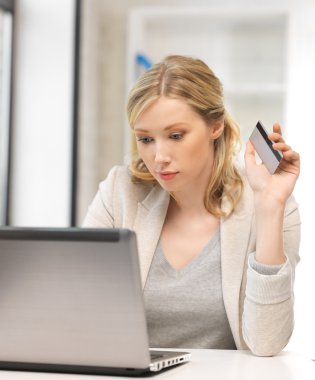 Serious woman with laptop computer and credit card clipart