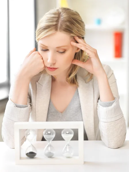 Pensive businesswoman with sand glass — Stock Photo, Image
