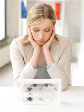 Pensive businesswoman with sand glass clipart