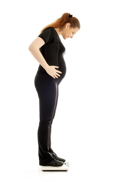 妊娠中の女性が自分自身の重量を量る — ストック写真