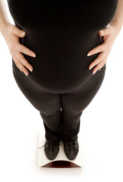 Pregnant lady weighing oneself, focus on belly — Stock Photo, Image