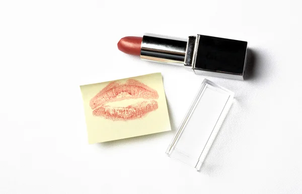 Red lipstick and yellow sticker note with kiss