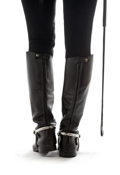 Beautiful legs in black leather horseman boots with riding-crop — Stock Photo, Image