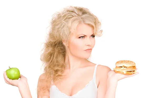 Femme au choix entre burger et pomme — Photo