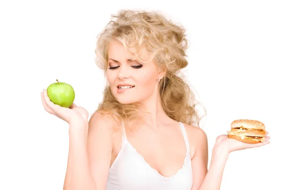 Mulher escolhendo entre hambúrguer e maçã — Fotografia de Stock