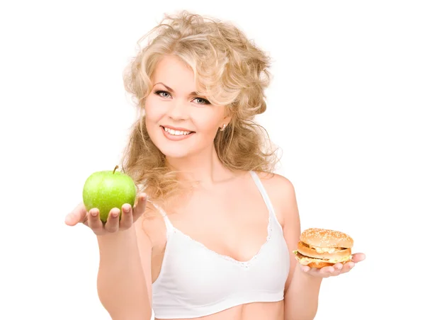 Женщина выбирает между бургером и яблоком — стоковое фото