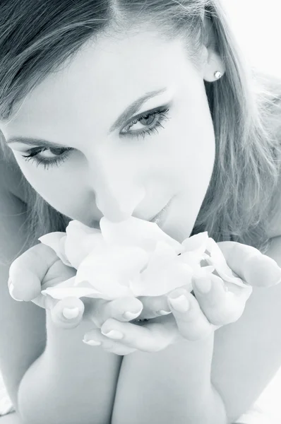 Mulher no spa cheirando pétalas de rosa branca — Fotografia de Stock