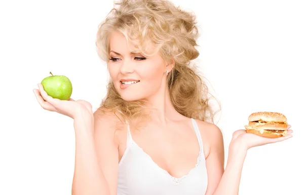 Kadın Burger ve apple arasında seçim yapma - Stok İmaj