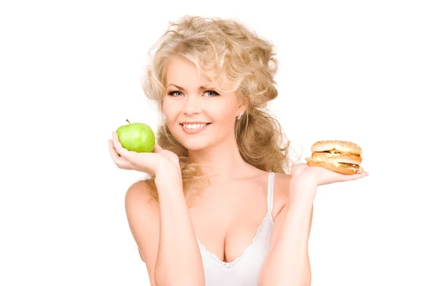 Женщина выбирает между бургером и яблоком Стоковая Картинка