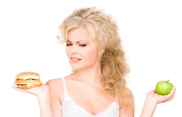 Žena volba mezi burger a jablko Stock Obrázky