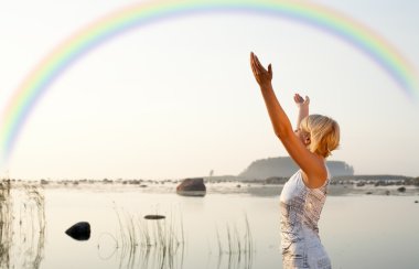 Pretty blond raising hands to the rainbow clipart