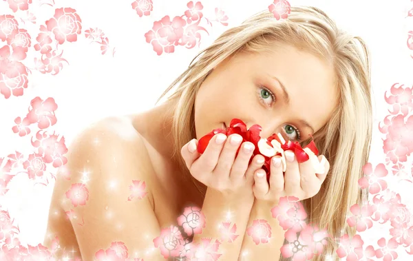 Schöne Blondine im Wellnessbereich mit roten und weißen Blütenblättern und Blumen — Stockfoto