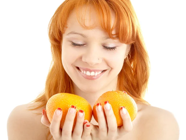 Веселая рыжая, держащая два апельсина над белым — стоковое фото