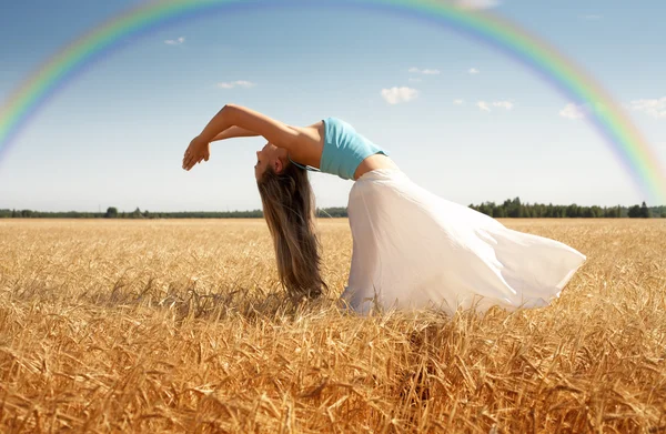 Stretching Frau auf der Wiese mit Regenbogen — Stockfoto