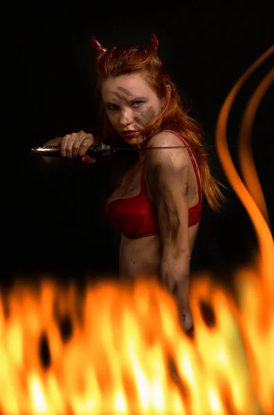 Dunkelrotes Teufelsmädchen mit Messer im Feuer — Stockfoto
