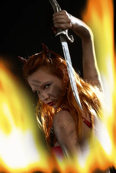 Chica demonio oscuro con un cuchillo en el fuego — Foto de Stock