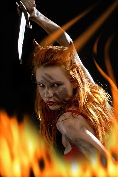 红魔鬼用小刀在火灾中的女孩 — 图库照片