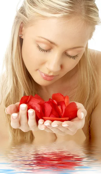 Schöne Blondine im Wasser mit roten Rosenblättern — Stockfoto