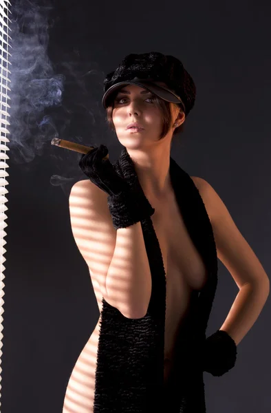 Woman in black astrakhan smoking cigar — Stock Photo, Image