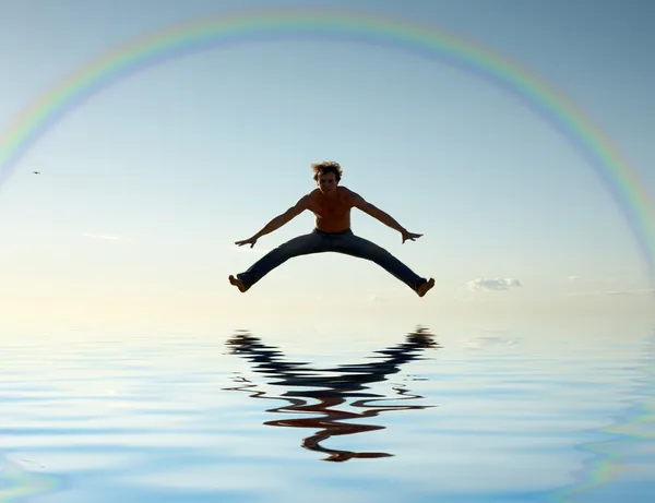Jump over water under rainbow — Stock Photo, Image