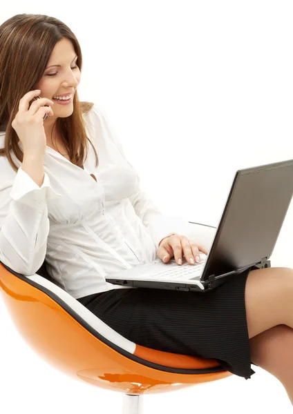 Businesswoman with laptop and phone in orange chair — Stock Photo, Image