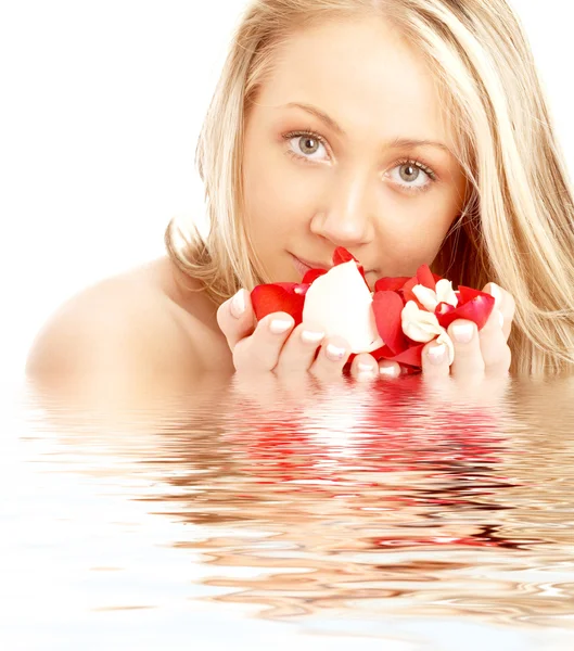 Biondo felice in acqua con petali rossi e bianchi — Foto Stock