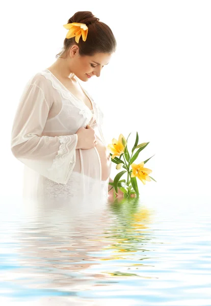 Беременная женщина с жёлтой лилией в воде — стоковое фото