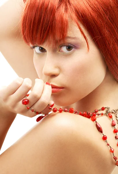 Redhead met rode kralen kijken over de schouder — Stockfoto