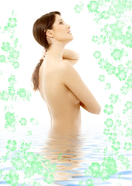 Linda morena em topless na água com flores — Fotografia de Stock