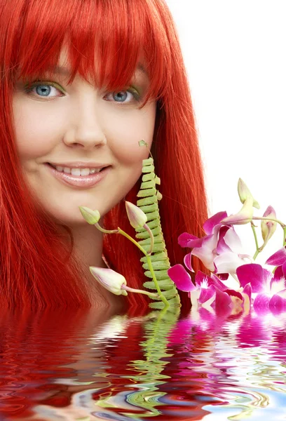 Прекрасная рыжая с орхидеей в воде — стоковое фото