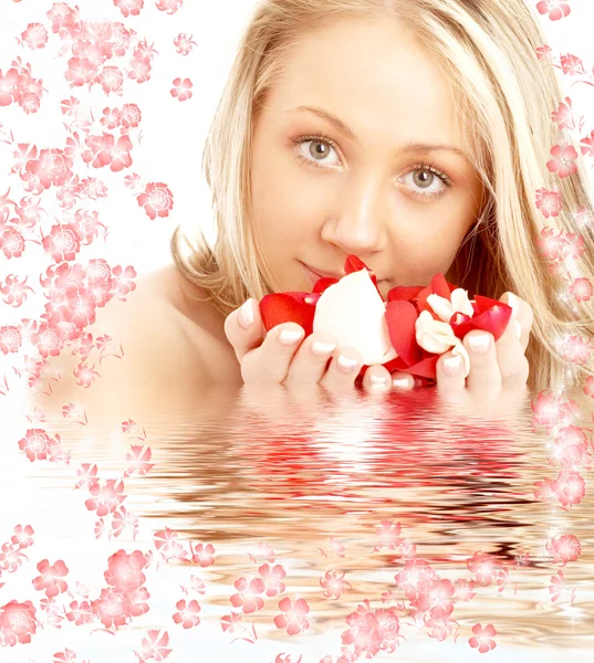 Loira feliz na água com flores vermelhas e brancas — Fotografia de Stock
