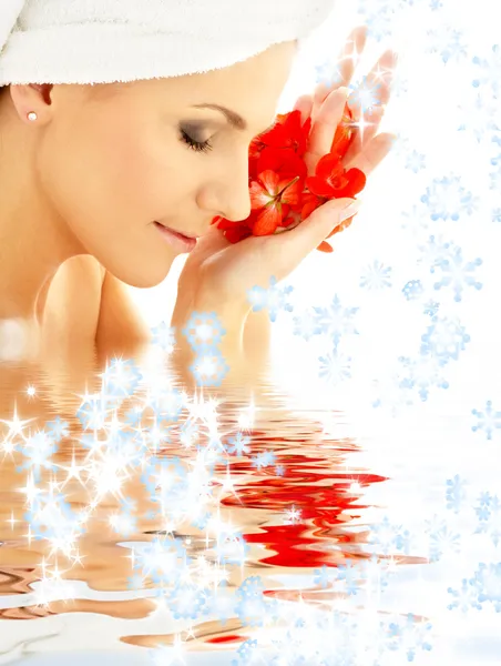 Dame met rode bloemblaadjes en sneeuwvlokken in water — Stockfoto